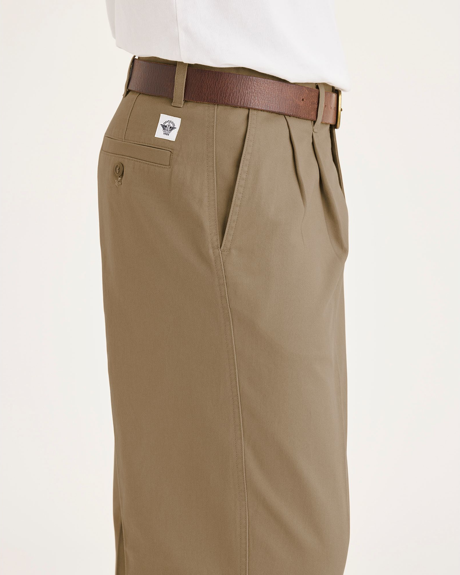 Side view of model wearing Harvest Gold Eighty-Six Original Pleated Chinos, Loose Fit.