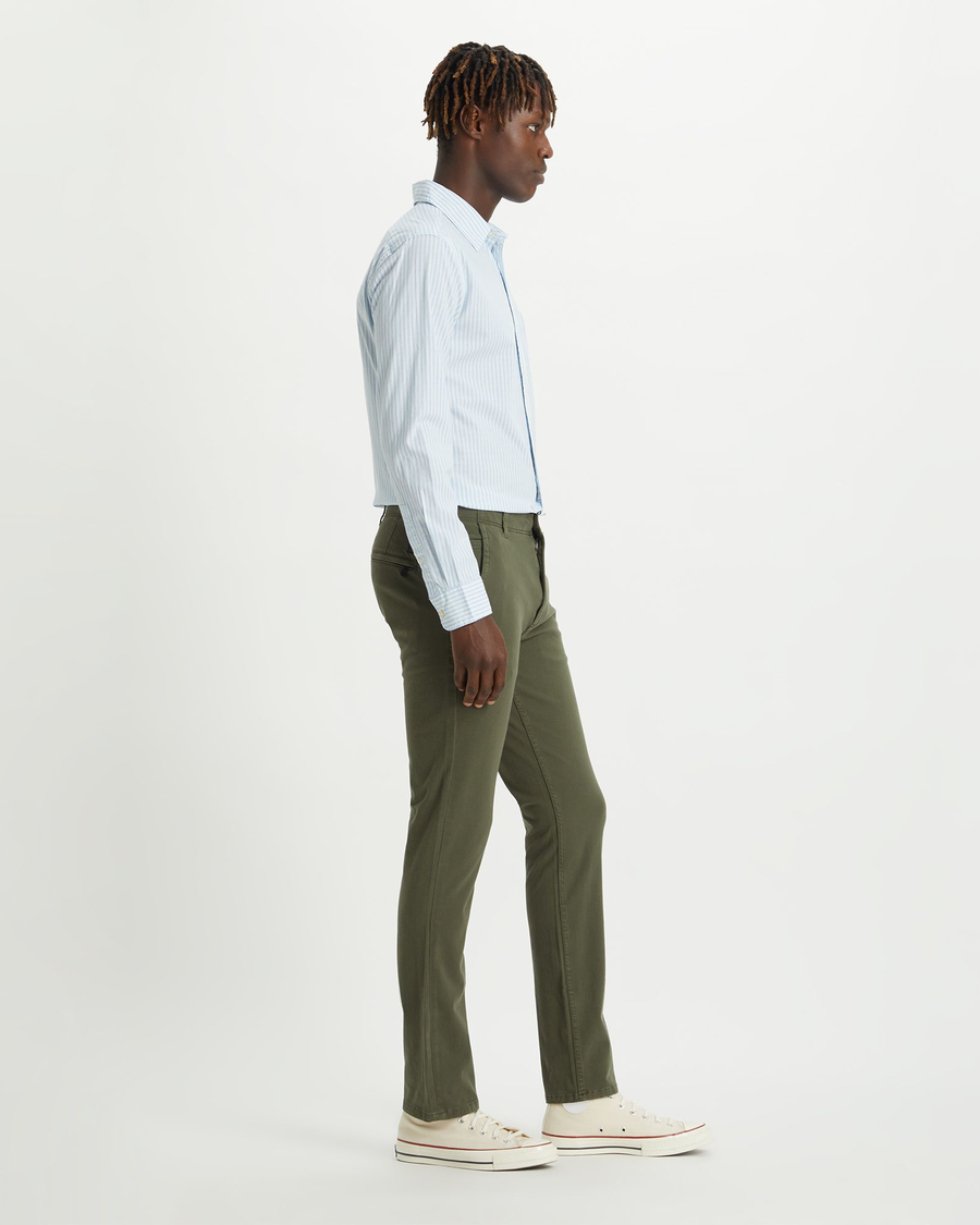 Side view of model wearing Olive Alpha Khakis, Skinny Fit.